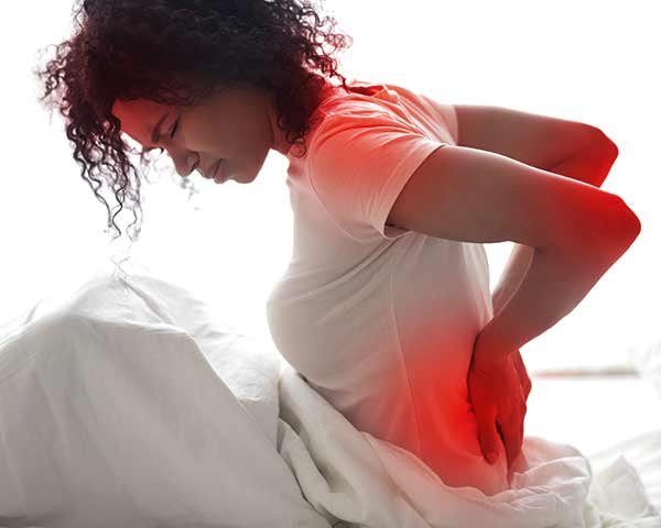 fibromyalgia-treatment-shoreside-pain-sarasota-florida Woman with fibromyalgia pain sitting up in bed holding lower back. Fibromyalgia treating at NWA Interventional Pain in Rogers, AR.