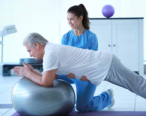 physical=therapy-shoreside-interventional-pain-sarasota-florida Man leaning on inflatable ball for physical therapy. NWA Interventional Pain, Rogers, AR.